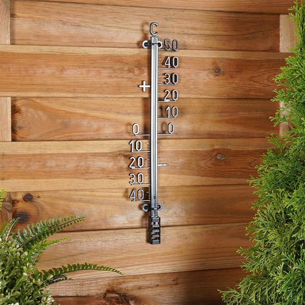 Un termómetro en una pared de madera muestra 20 grados Celsius.