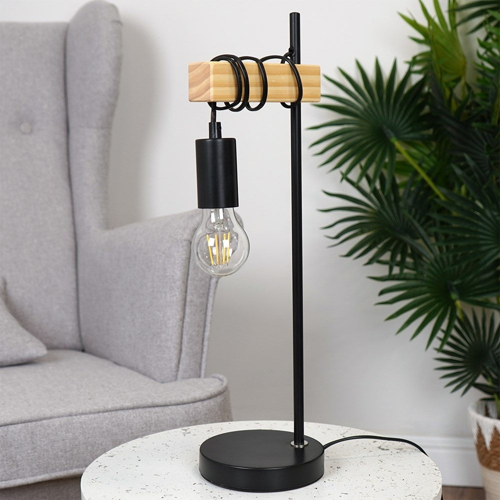 Lámpara de noche moderna con bloque de madera, pantalla negra y bombilla expuesta.