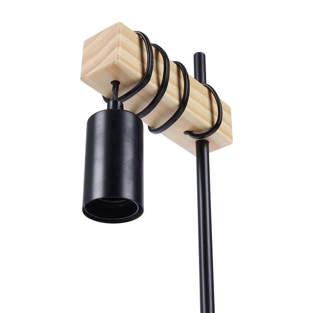 Una pantalla de lámpara negra cuelga de una viga de madera con espirales negras.