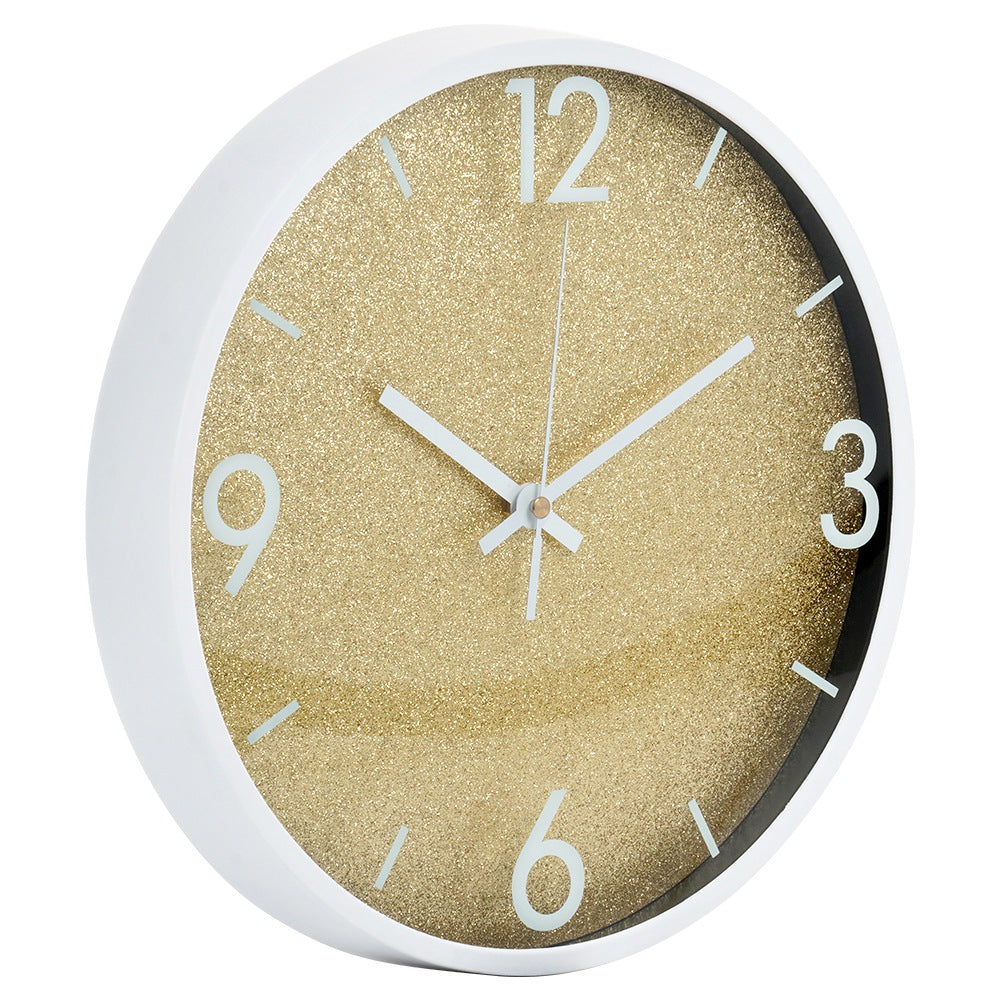 Un reloj de pared blanco con esfera dorada brillante y manecillas blancas.
