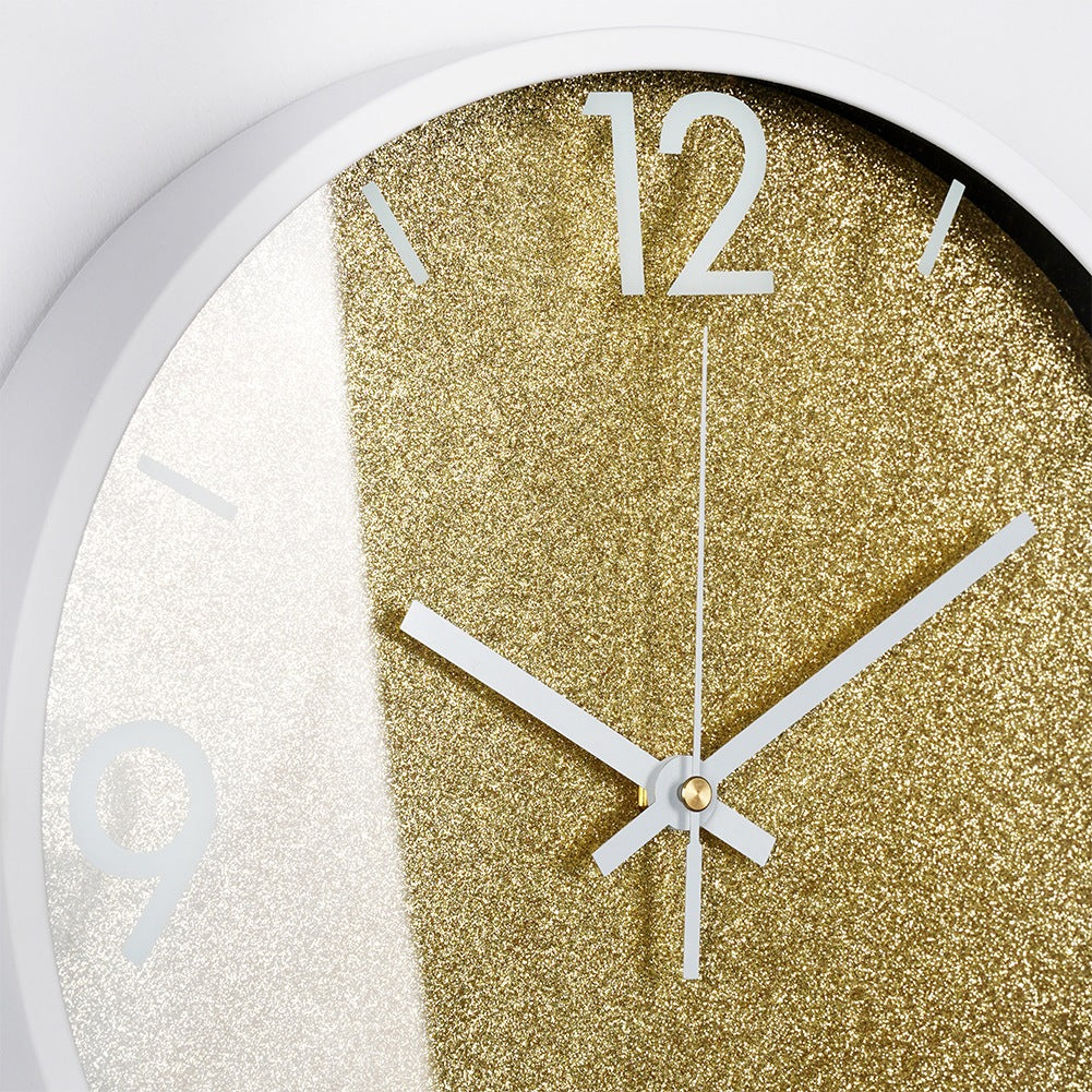 Primer plano de un reloj de pared con esfera dorada brillante y manecillas blancas.