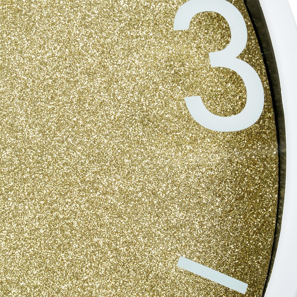 Esfera de reloj dorada con purpurina, número blanco 3 y una raya.