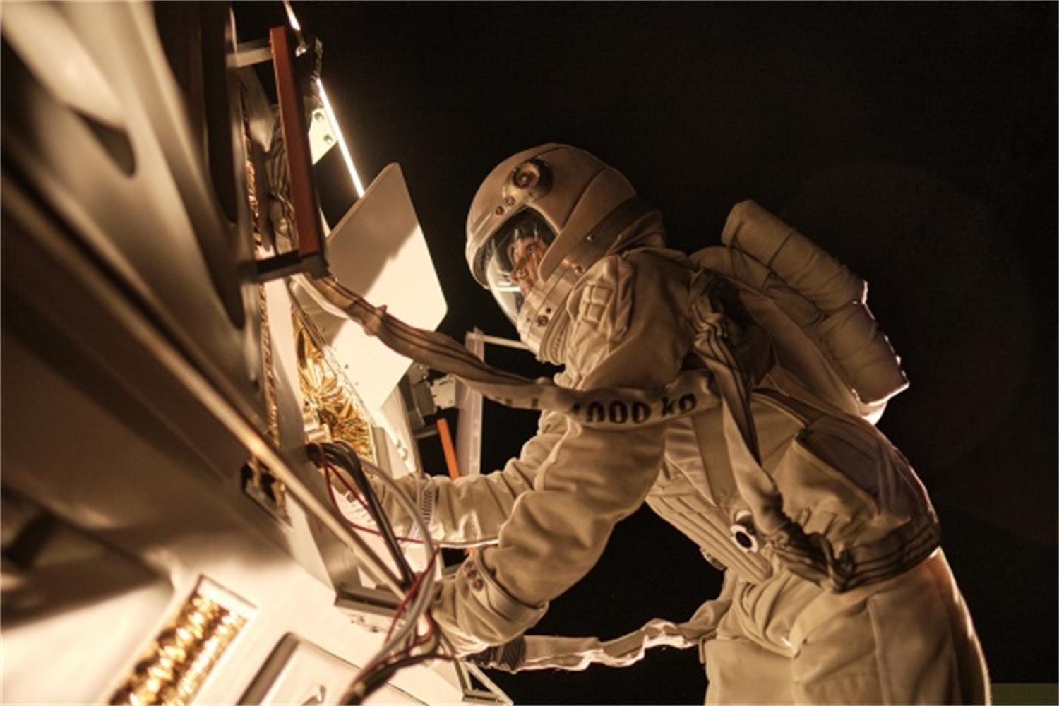 Un astronauta in tuta spaziale bianca lavora su una macchina con molti fili.