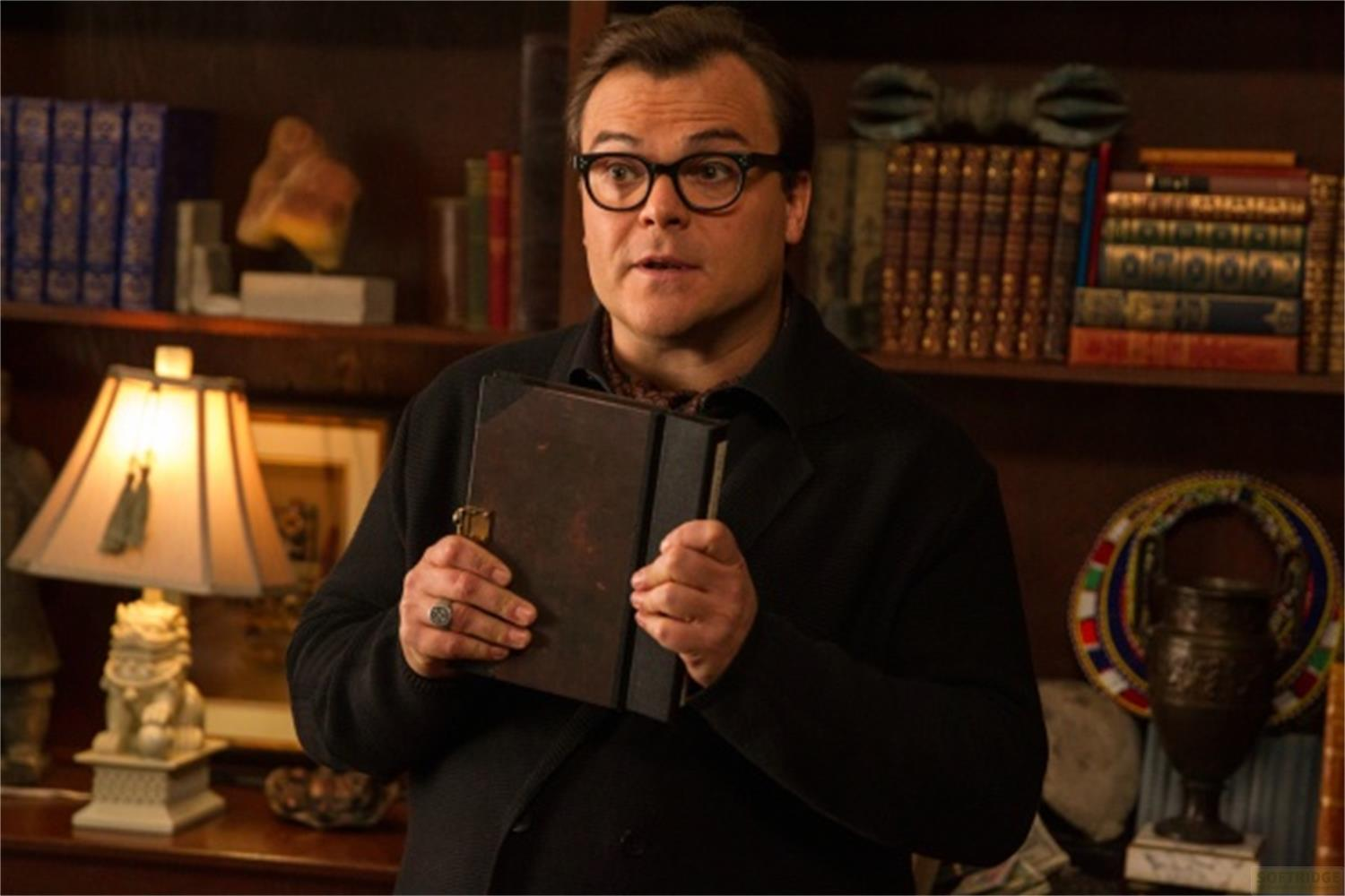 Uomo con occhiali tiene un vecchio libro in una stanza con librerie.