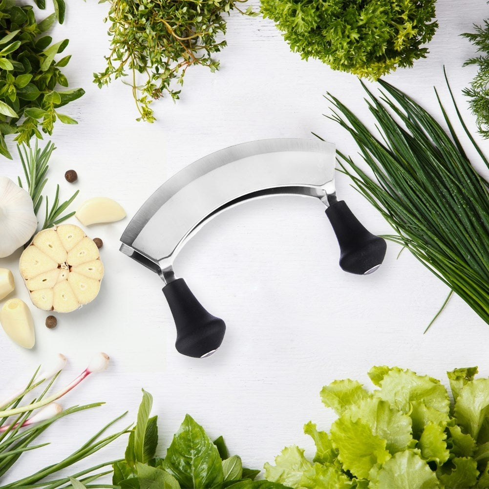 Media cabeza de ajo, hierbas y un cuchillo mezzaluna sobre madera blanca.