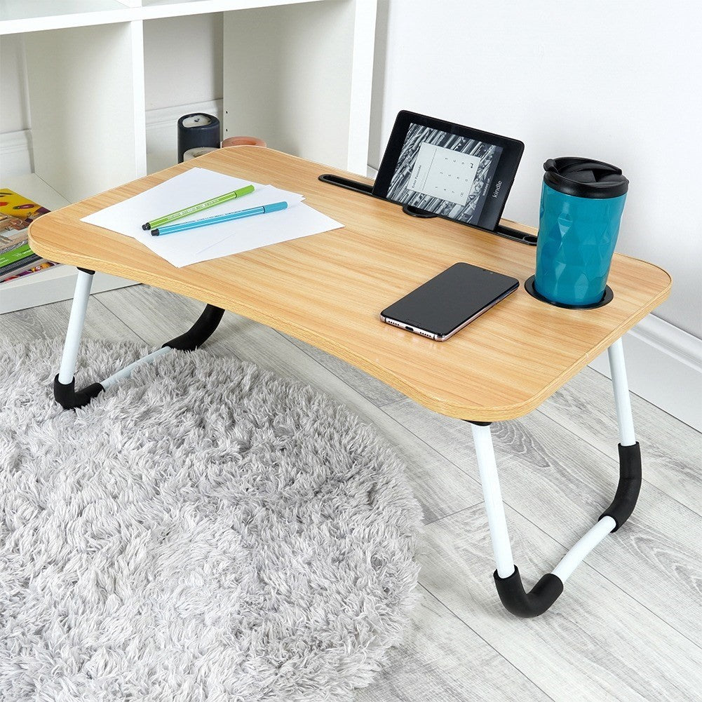 Un escritorio de regazo de madera con tablet, teléfono, taza y bolígrafos.