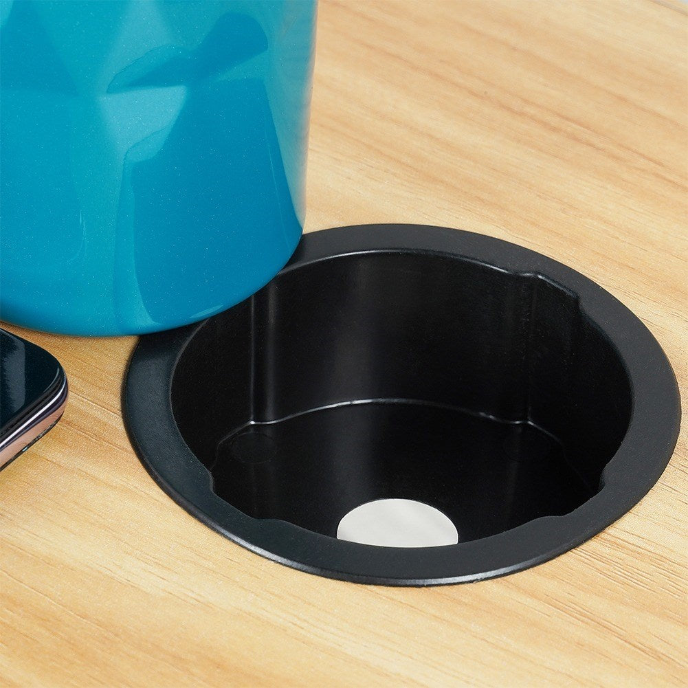 Una taza turquesa en un portavasos negro sobre superficie de madera.