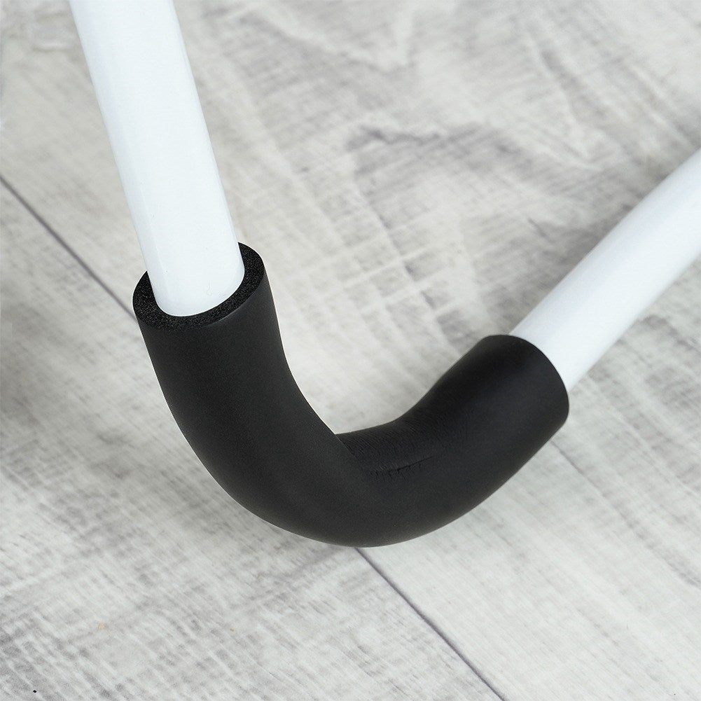 Un tubo blanco envuelto en espuma negra se dobla sobre un suelo de madera.