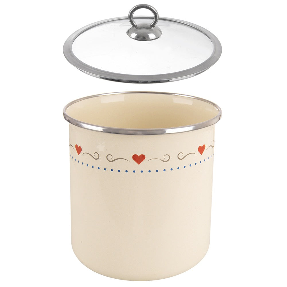 Una olla color crema con un patrón de corazón y tapa de cristal.