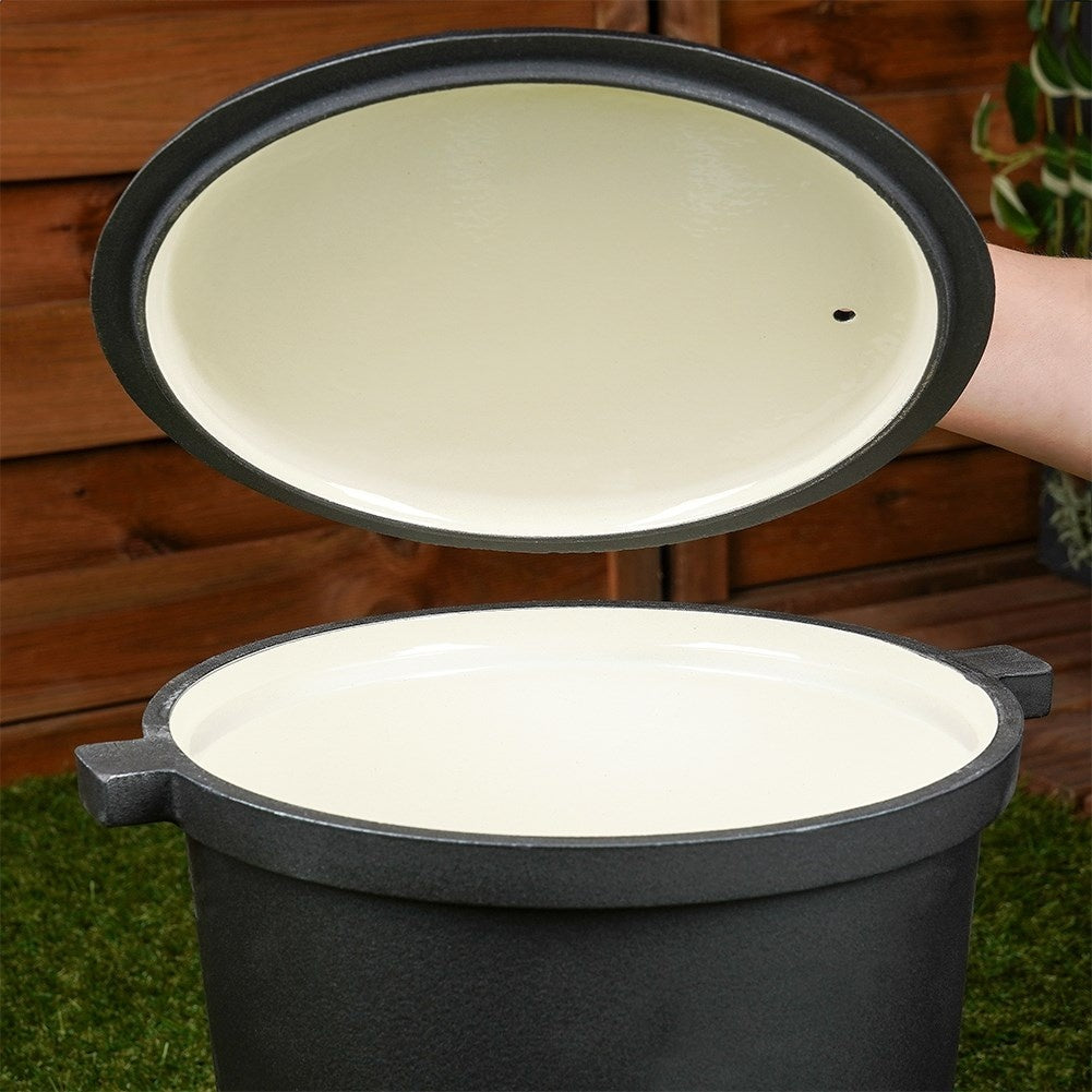 Una olla abierta de hierro fundido negro con interior color crema sobre hierba.