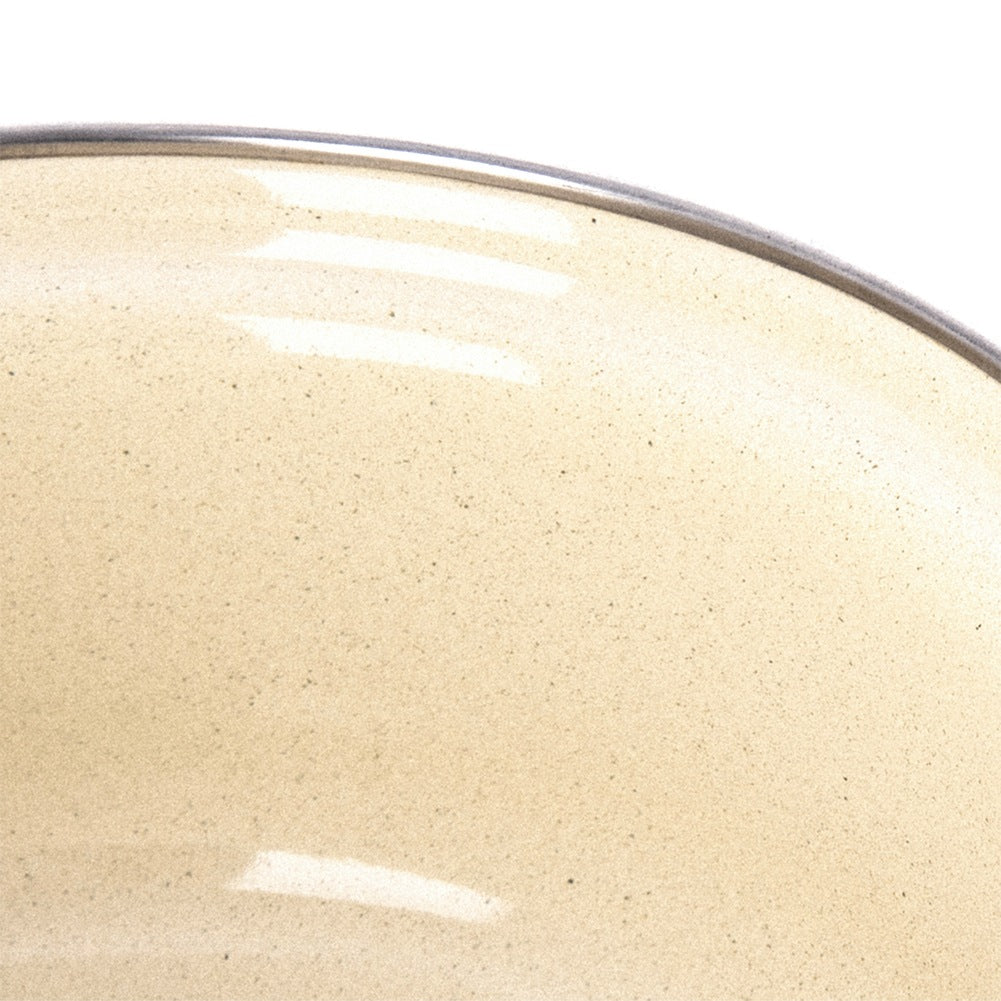 Primer plano de un cuenco de color crema con motas oscuras y borde oscuro.