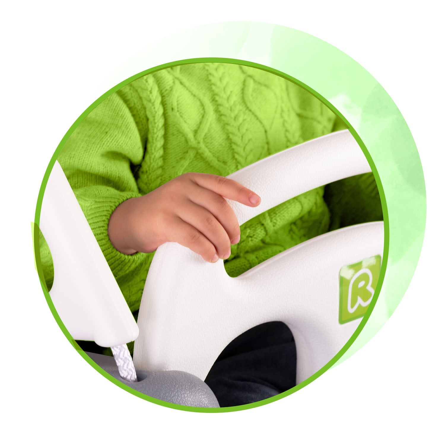 Niño con jersey verde sujeta el volante de un coche de juguete.
