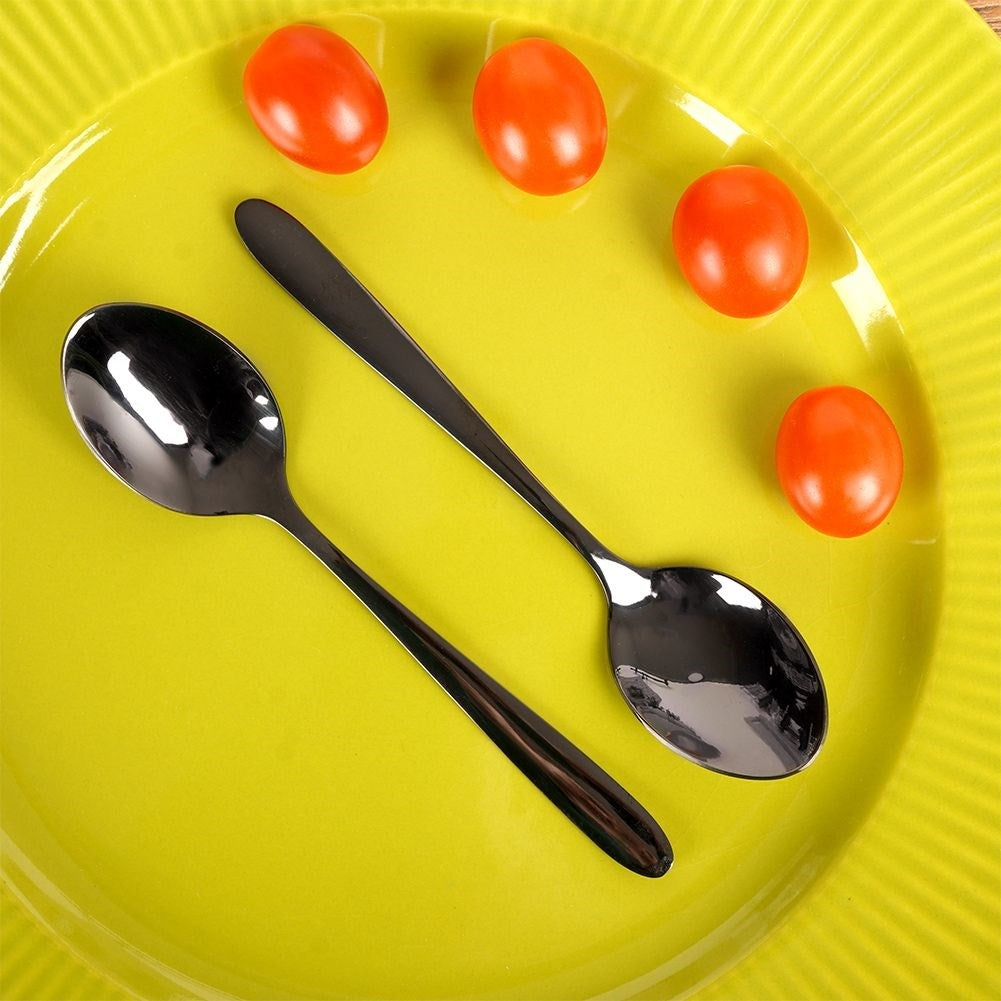 Dos cucharas y cuatro tomates cherry en un plato amarillo.