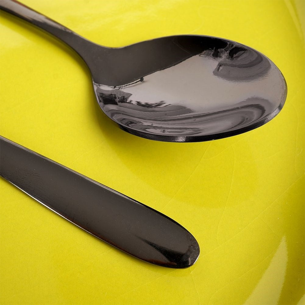 Una cuchara y un cuchillo negros sobre un plato amarillo.