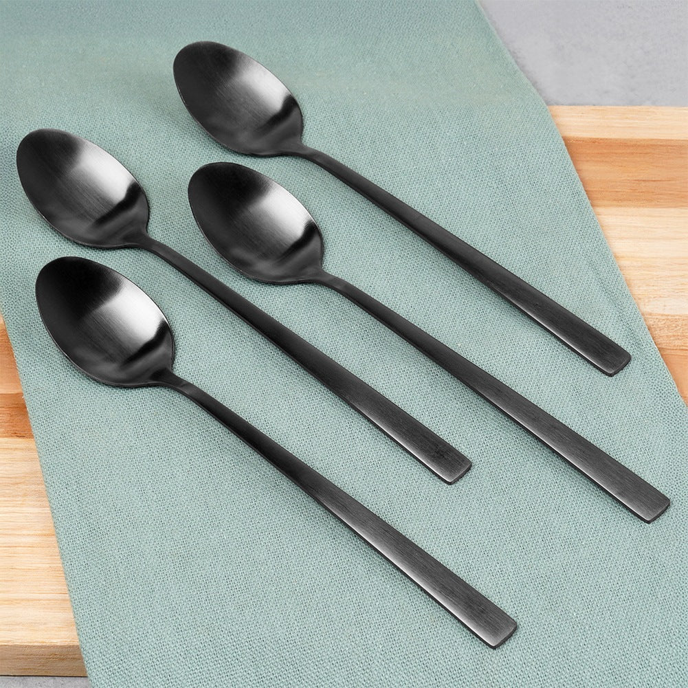 Cuatro cucharas negras sobre un paño turquesa.
