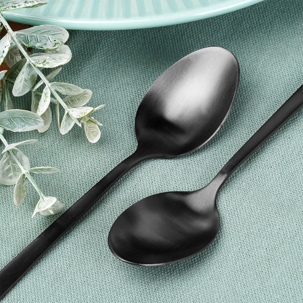 Dos cucharas negras descansan sobre un mantel verde menta junto a plantas.
