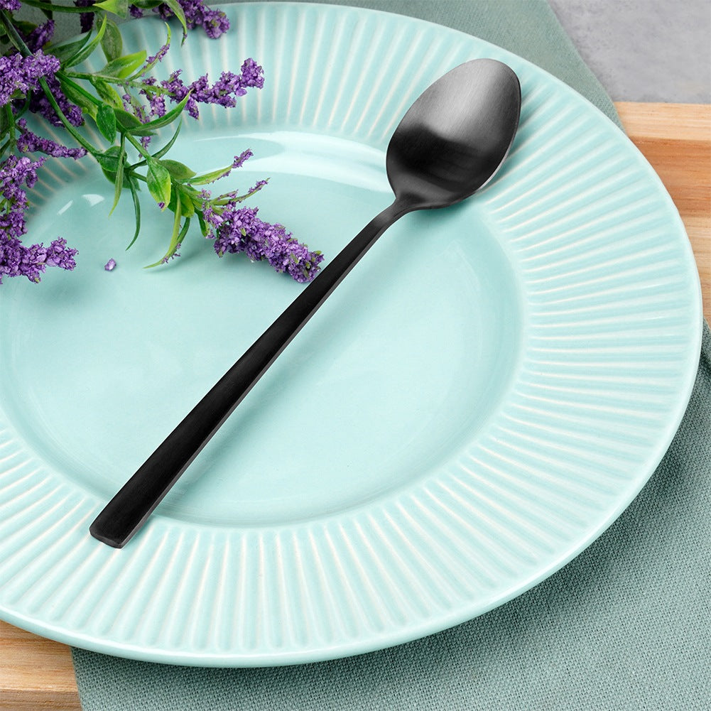 Una cuchara negra descansa sobre un plato azul claro con ramitas de lavanda.