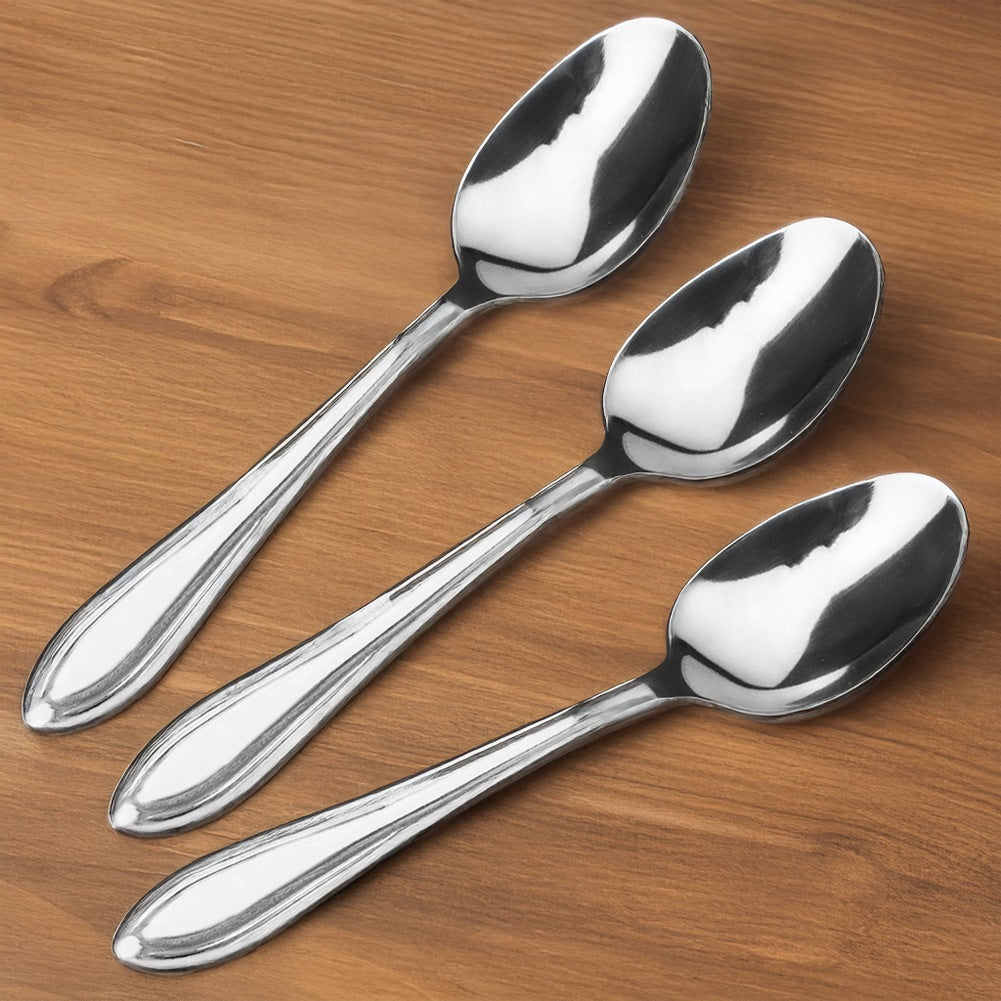 Tres cucharas brillantes sobre una mesa de madera.