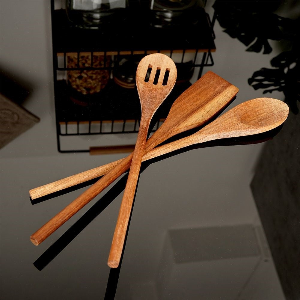 Tres utensilios de cocina de madera sobre una superficie negra. Uno tiene ranuras.