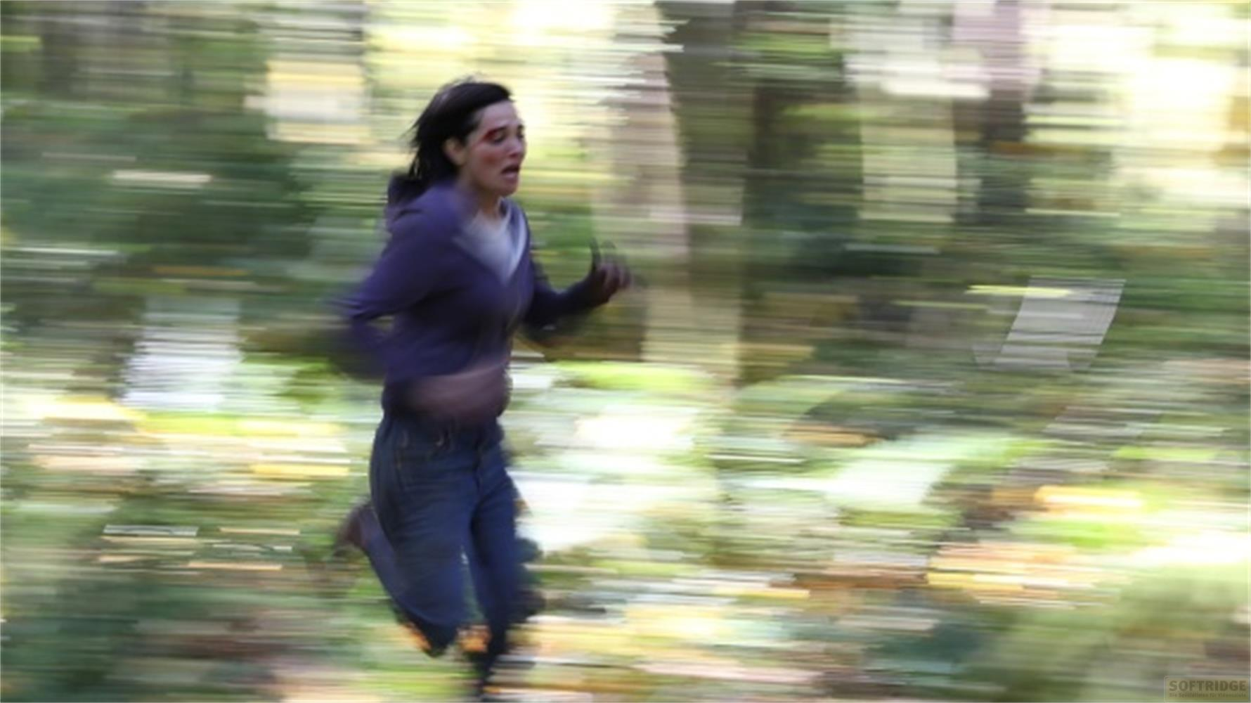 Donna con ferita al viso corre in una foresta sfocata.