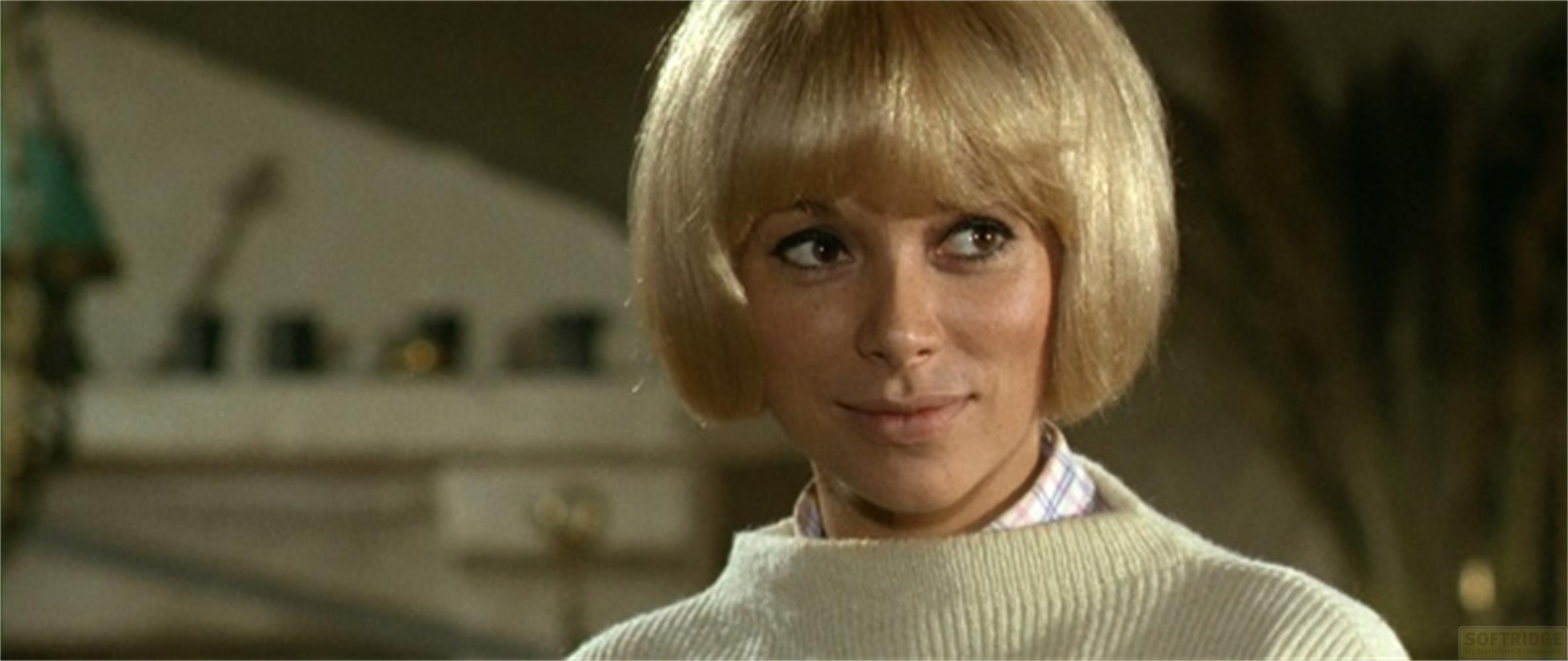 Una donna con taglio a caschetto e maglione guarda di lato.