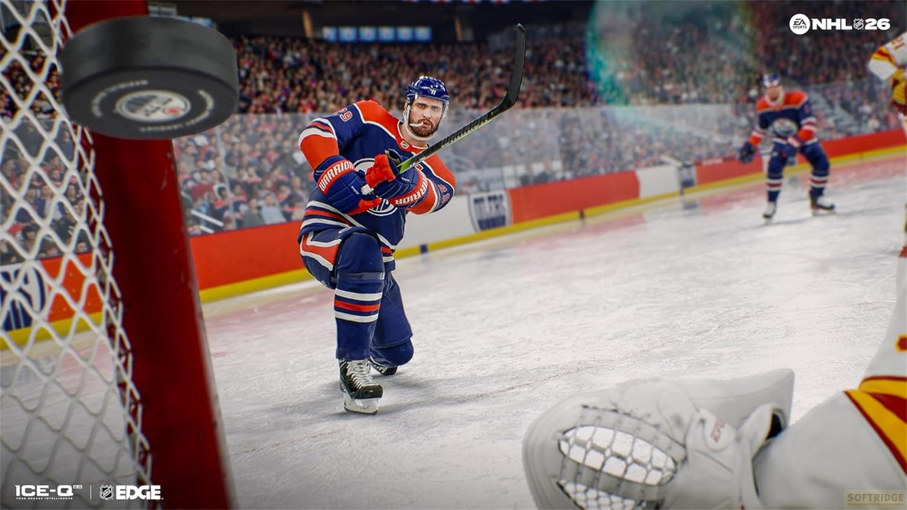 Eishockeyspieler im blauen Trikot schlägt den Puck, der im Netz hängt.