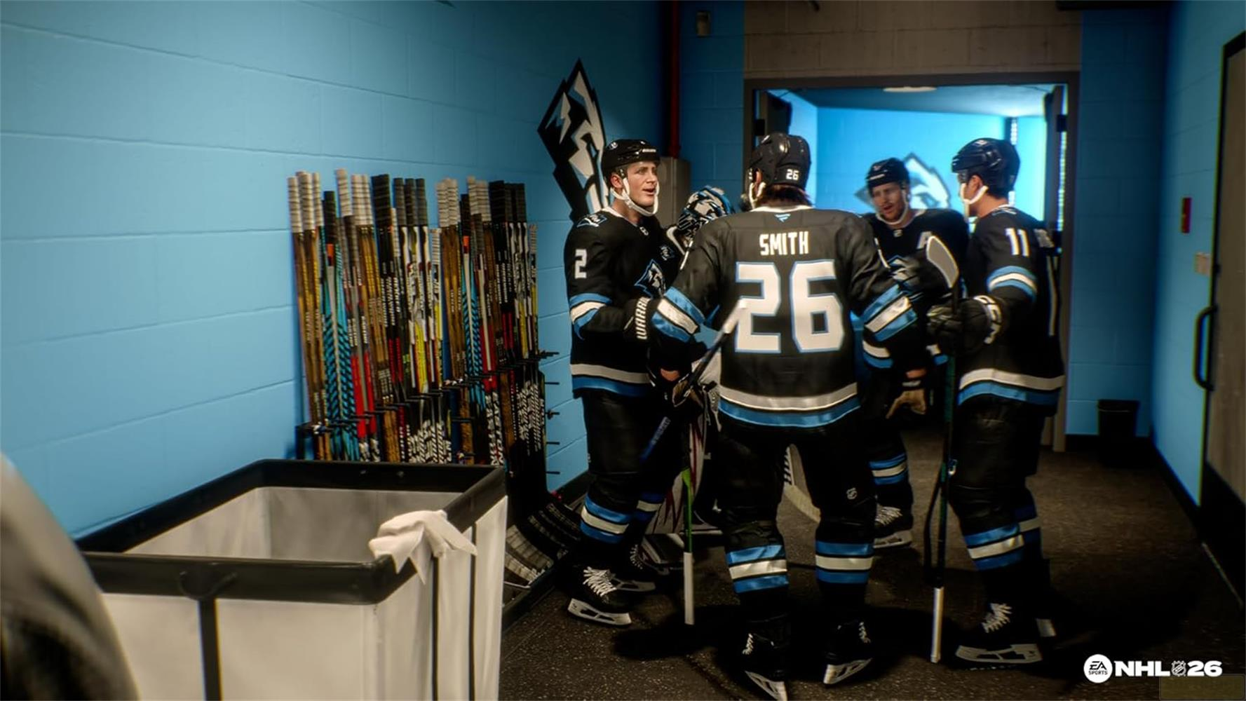 Eishockeyspieler in Schwarz-Hellblau-Trikots unterhalten sich in der Umkleidekabine neben vielen Schlägern.