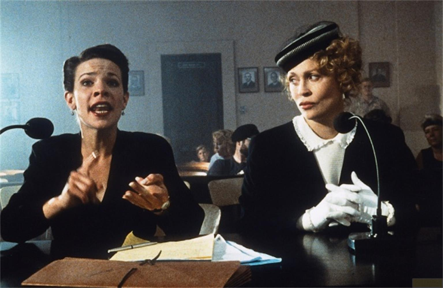 Due donne parlano ai microfoni in una stanza con quadri al muro.