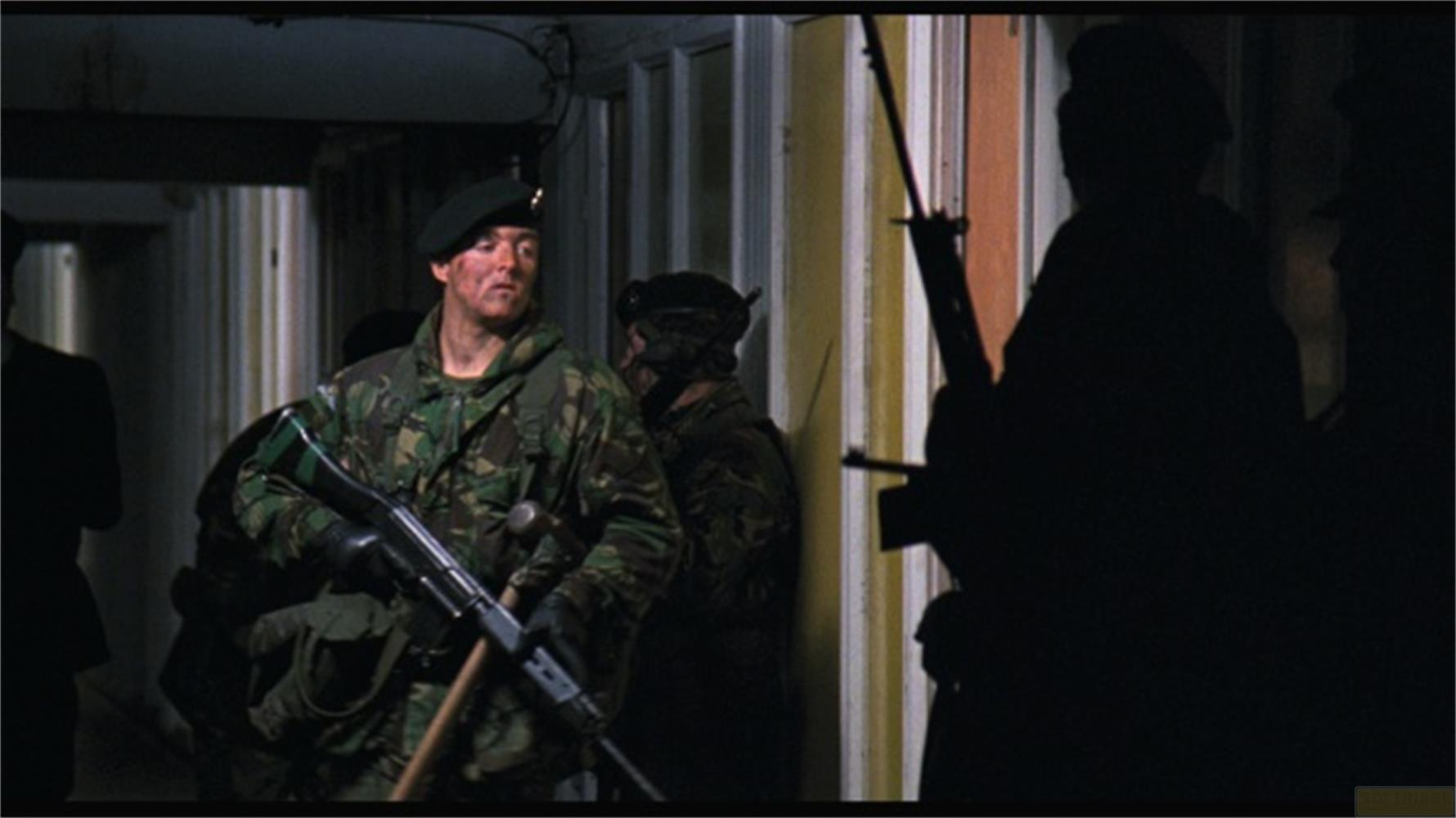 Soldaten in Tarnanzügen und grünen Baretts mit Gewehren in einem dunklen Gang.