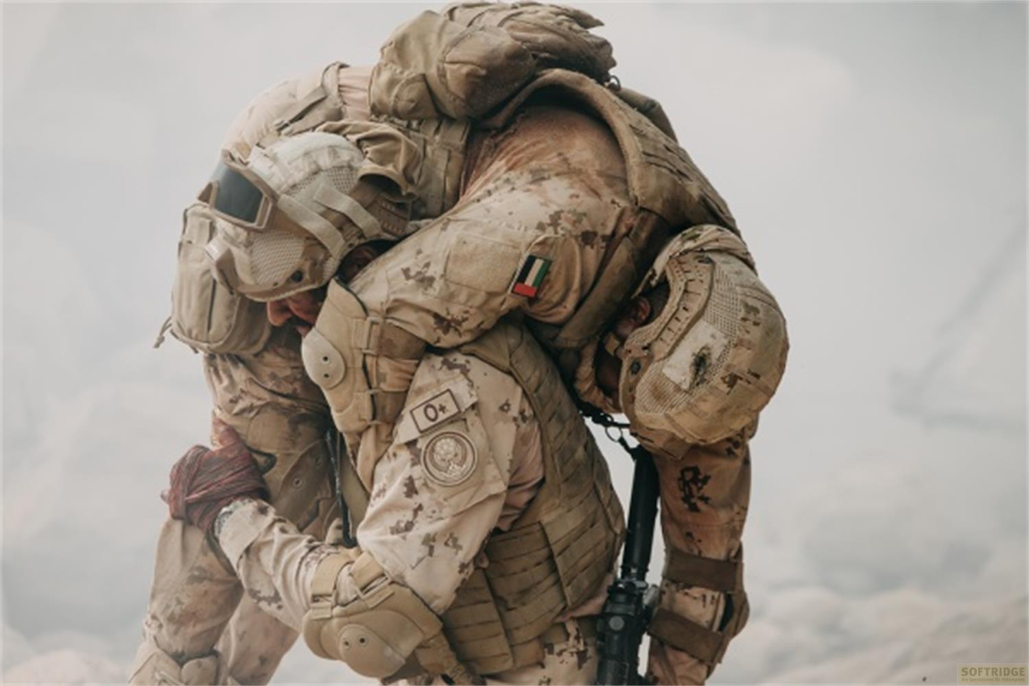 Un soldato trasporta un altro soldato ferito. Entrambi indossano uniformi mimetiche.