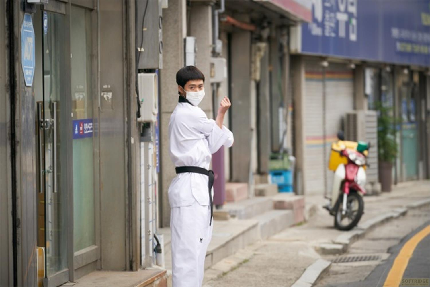 Una persona in divisa da Taekwondo e mascherina in strada.