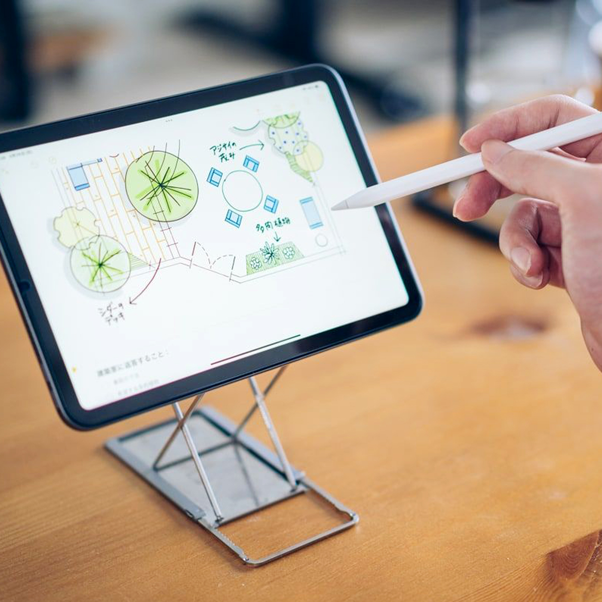 Dłoń używa rysika do szkicowania planu ogrodu na tablecie.