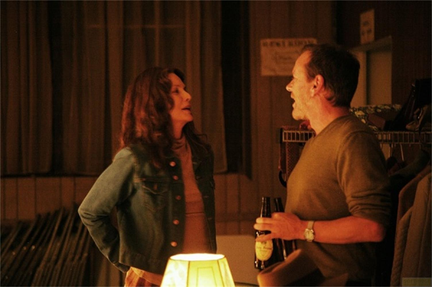 Un uomo e una donna parlano in una stanza. L'uomo tiene una bottiglia di birra.