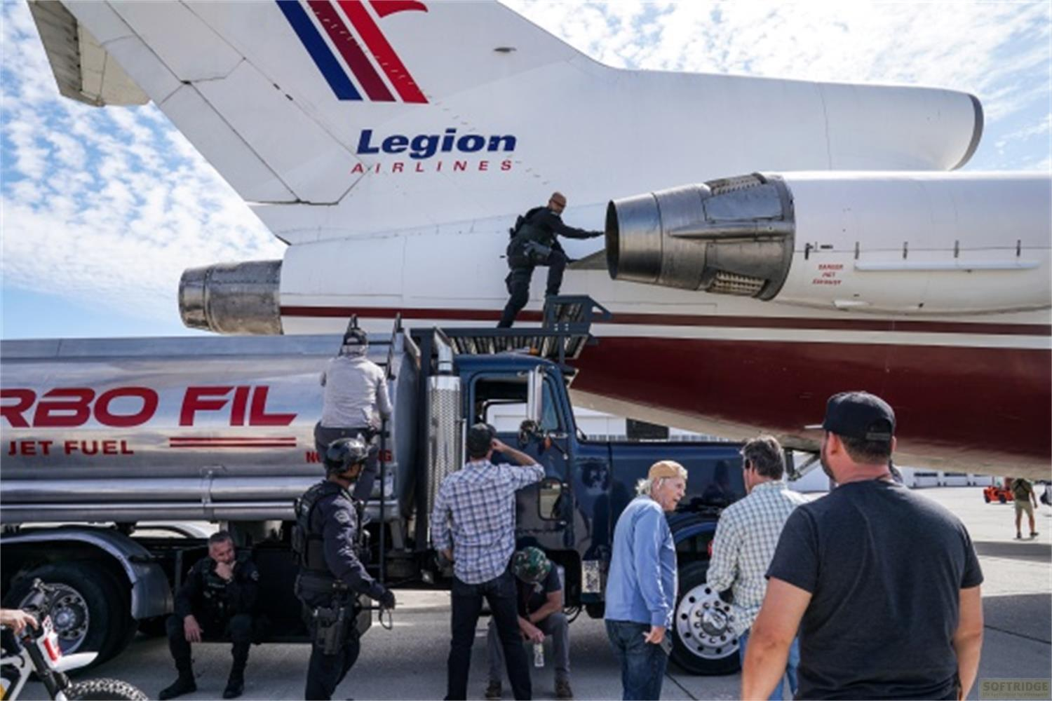 Un uomo su un camion accanto a un aereo mentre un'autocisterna fa rifornimento.