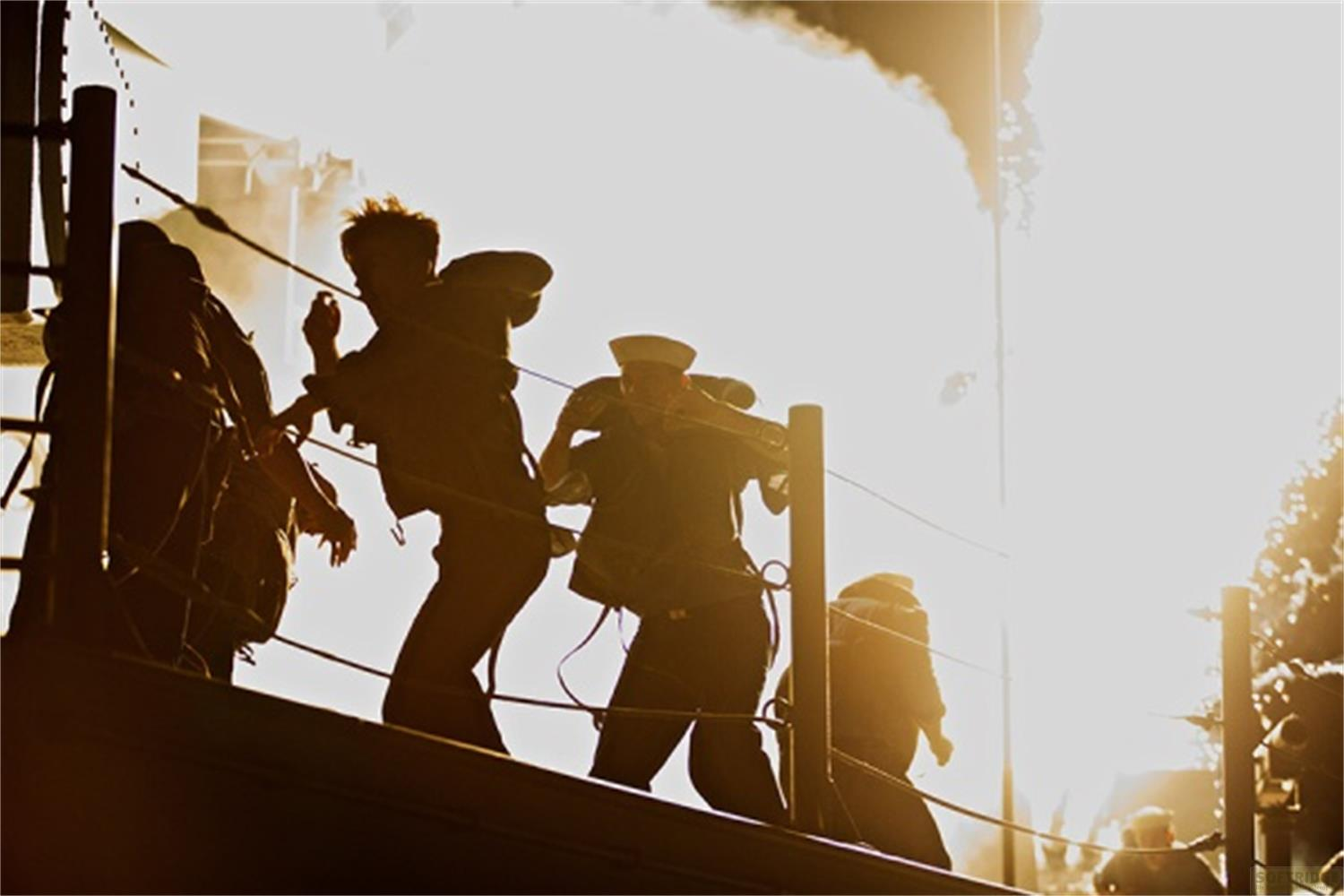 Personnages en uniforme en silhouette sur le pont d'un navire, soleil éclatant et fumée.