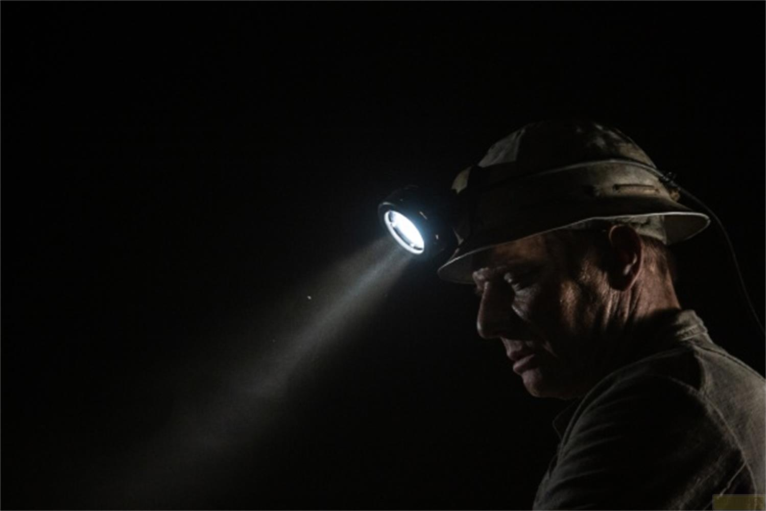 Un uomo con lampada frontale al buio, la luce brilla in avanti.