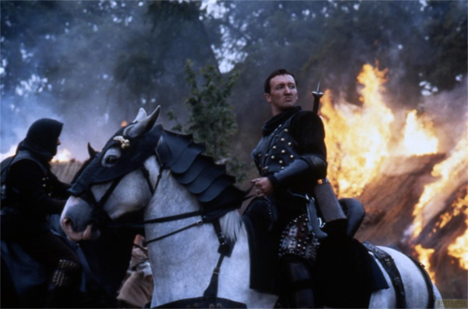 Un homme en armure sur un cheval chevauche devant un bâtiment en feu.