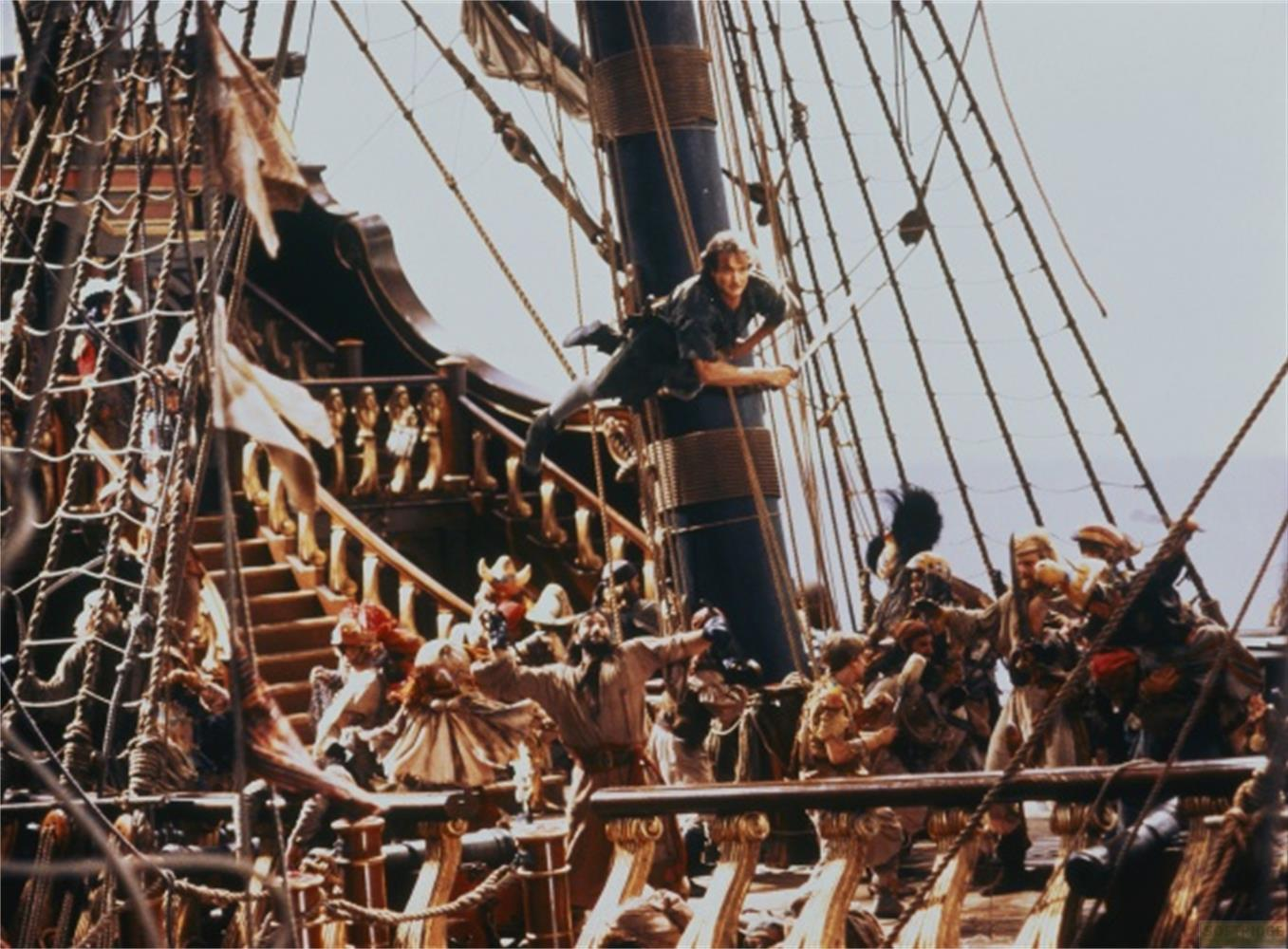 Un homme se balance sur une corde au-dessus d'un navire pirate avec de nombreux
membres d'équipage sur le pont.