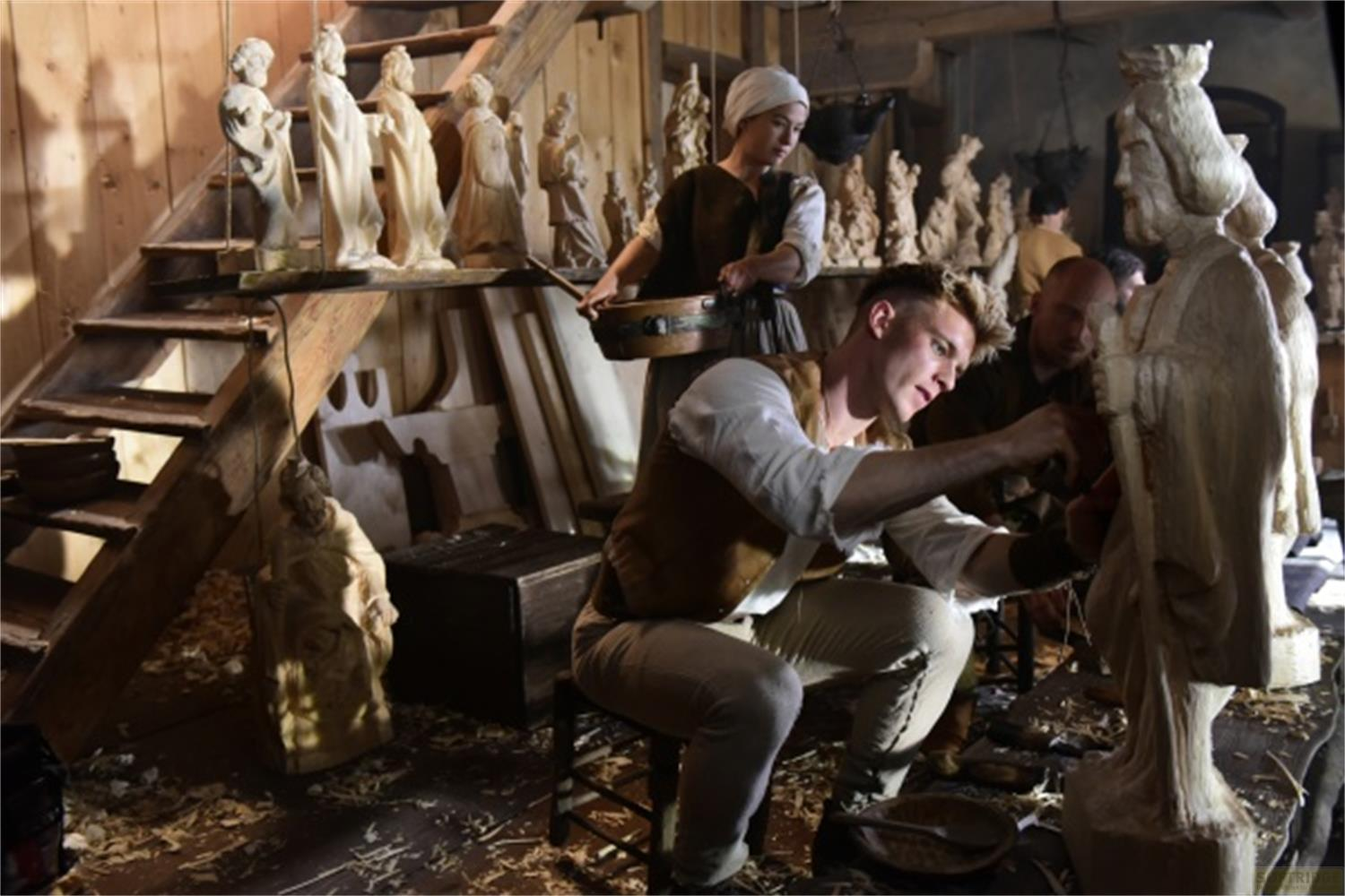 Intagliatori di legno lavorano su figure in un laboratorio. Trucioli di legno sul pavimento.