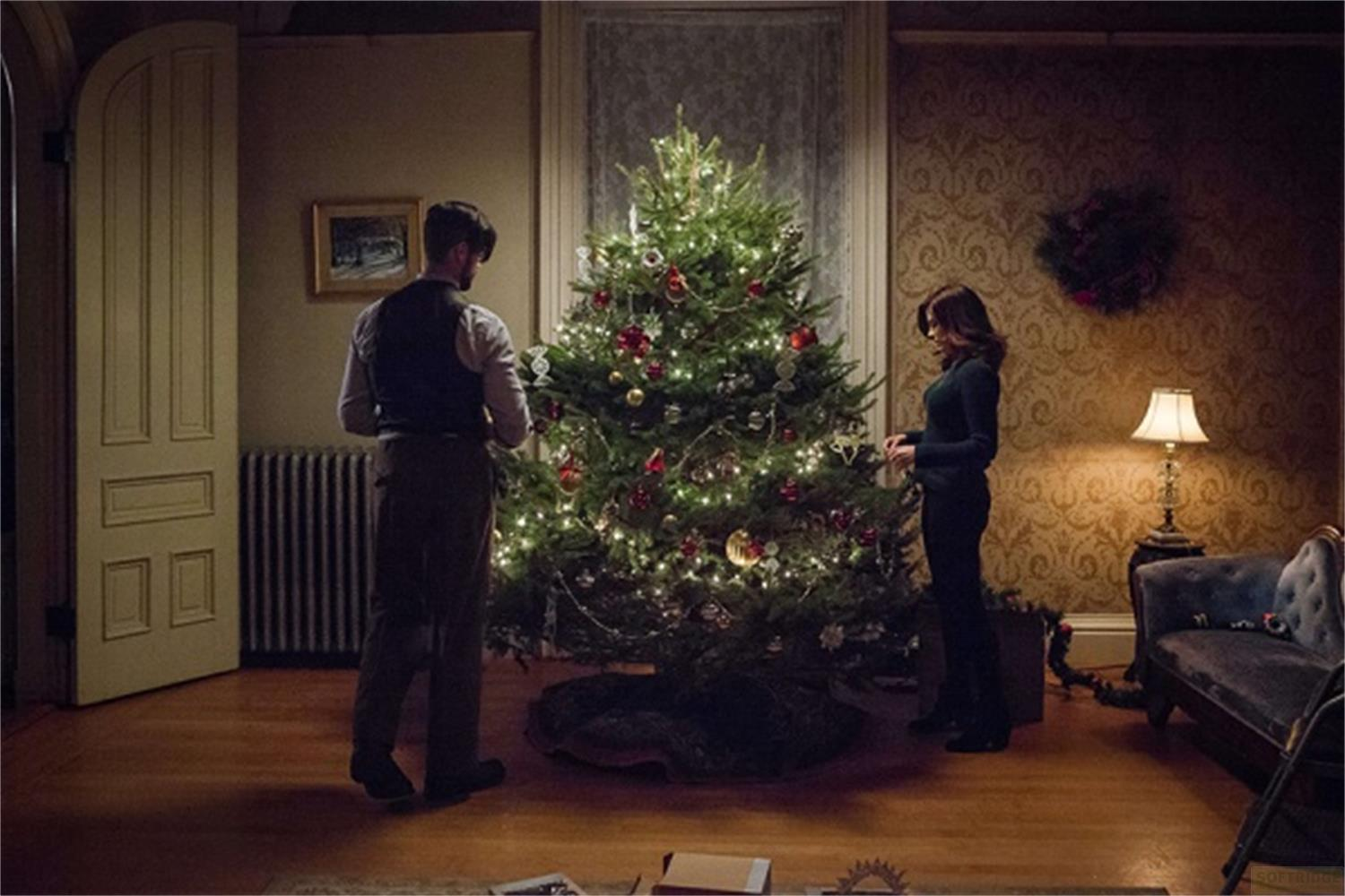 Un uomo e una donna decorano un albero di Natale con luci e ornamenti.