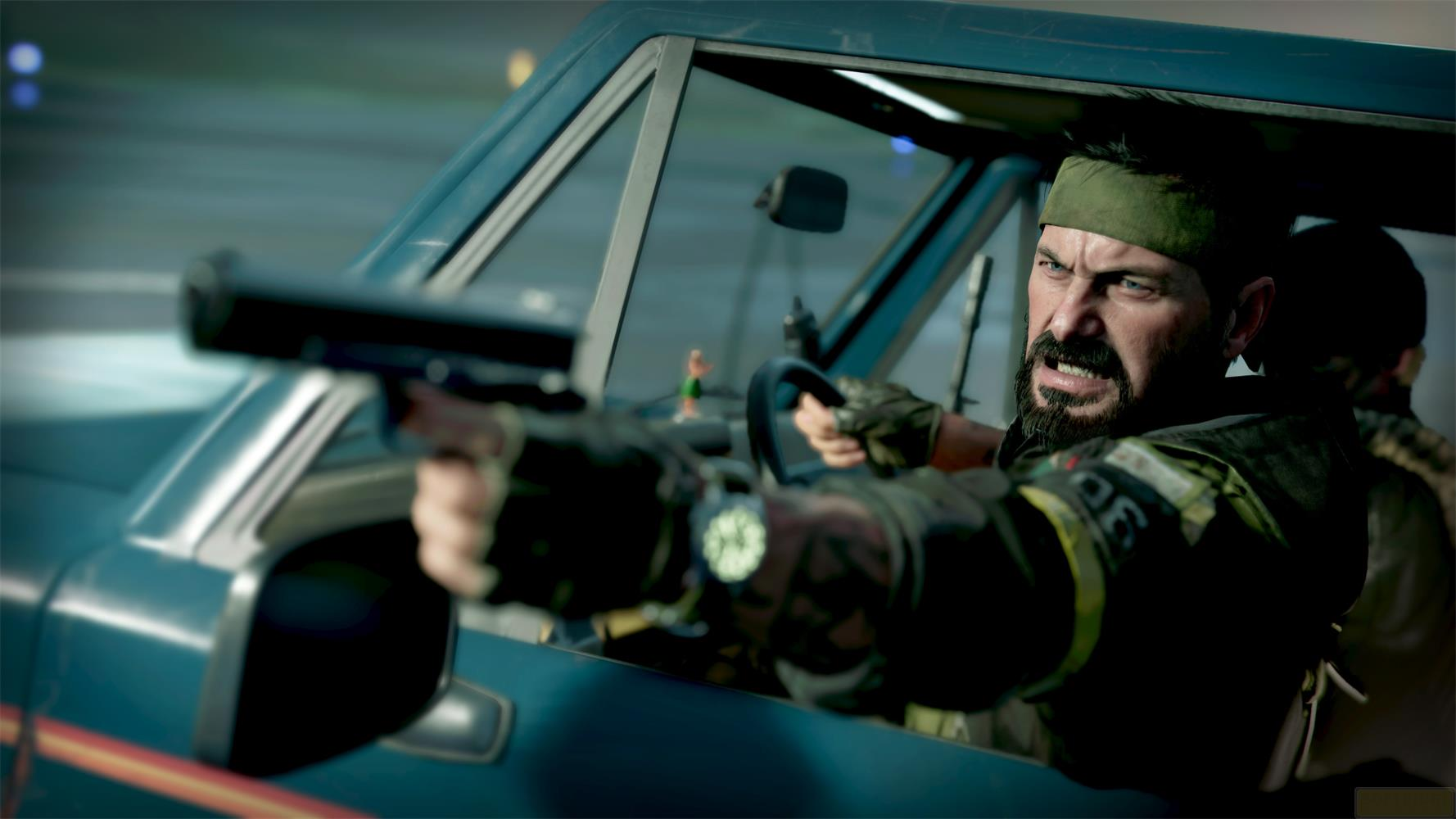 Un uomo con bandana punta una pistola da un veicolo in movimento.