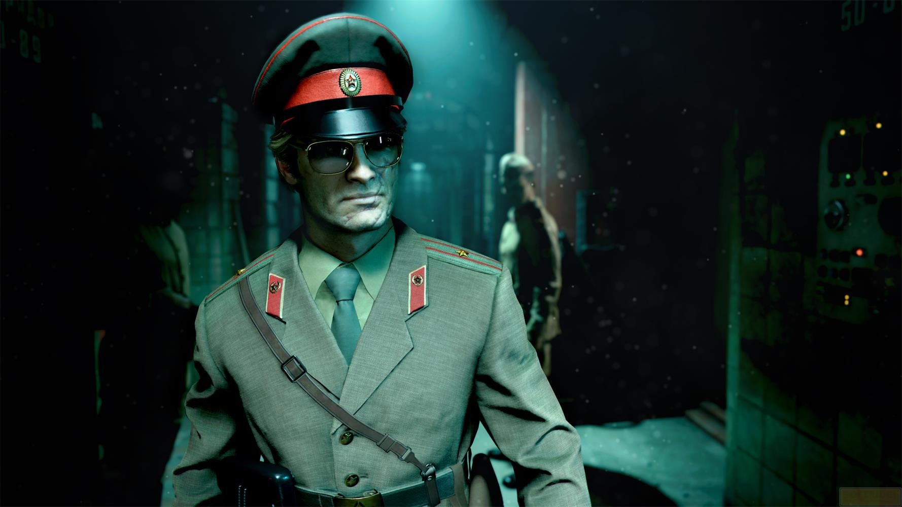 Uomo in uniforme militare con occhiali da sole e cappello rosso, figure sullo sfondo.