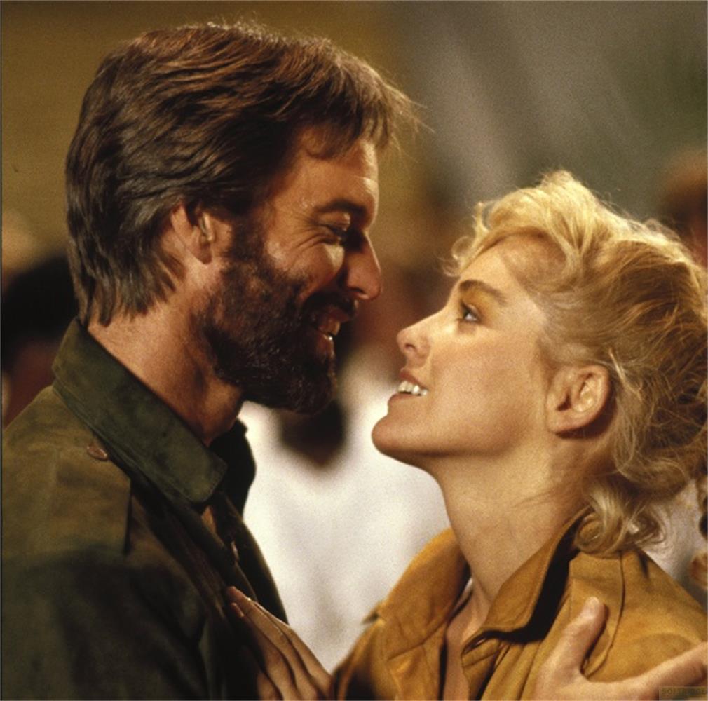 Un homme barbu et une femme blonde se regardent avec amour.