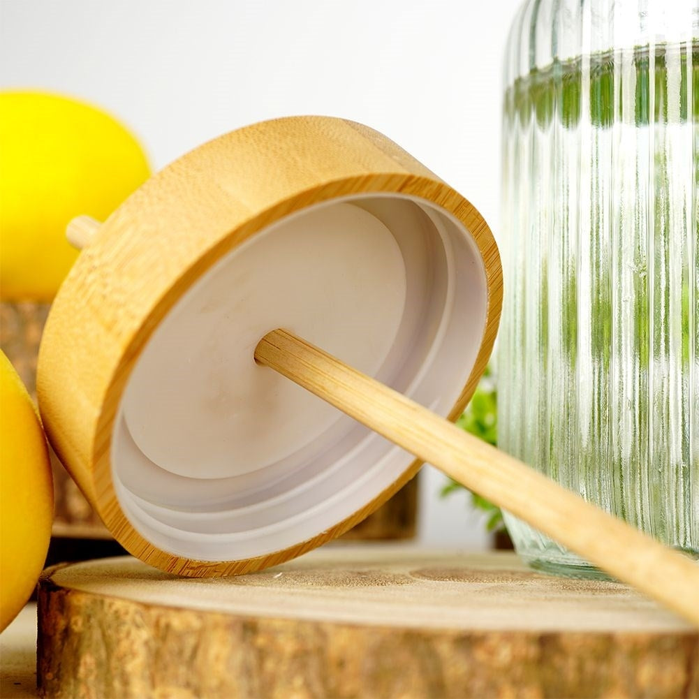 Una tapa de madera descansa sobre rodajas de madera junto a limones y un vaso.