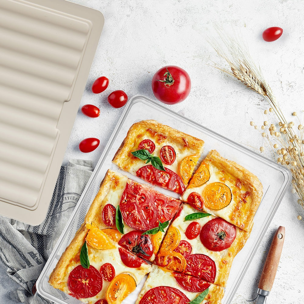 Una pizza rectangular de tomate con queso, albahaca y tomates cherry en un plato de cristal.