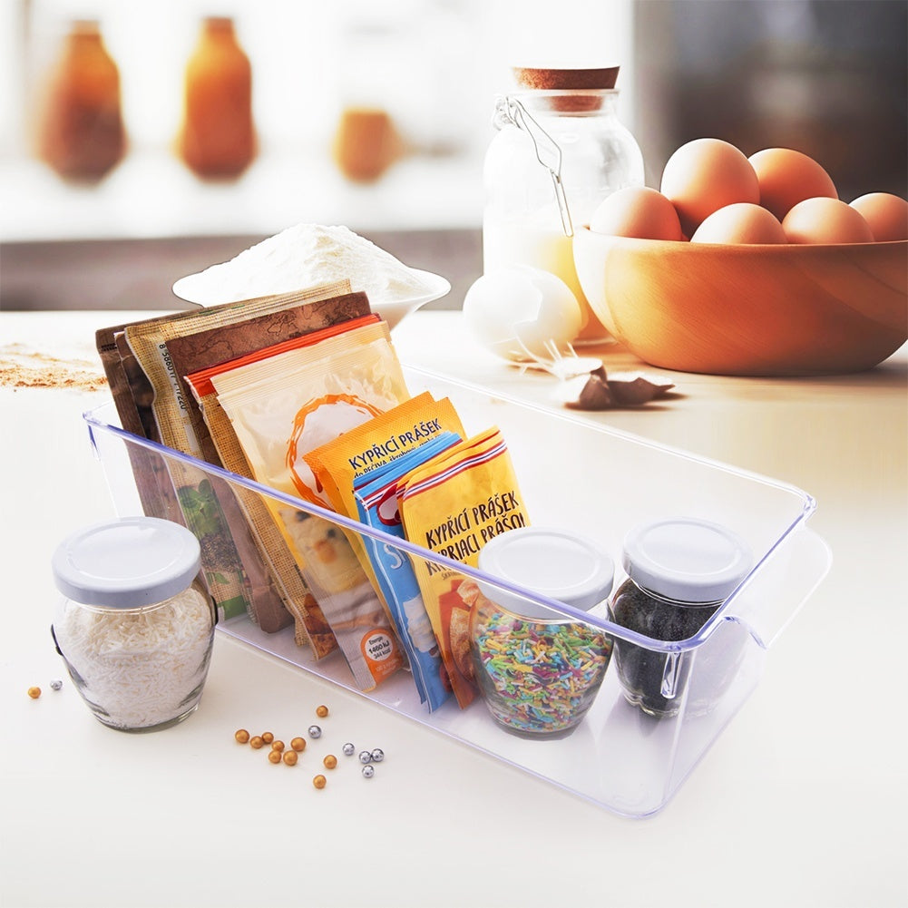 Contenedor transparente con ingredientes para hornear: huevos, harina, especias en bolsas.