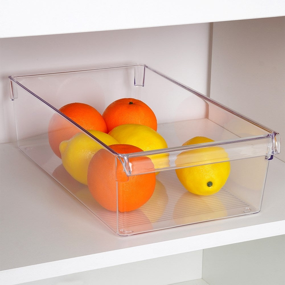 Naranjas y limones en una caja de almacenamiento transparente en un estante blanco.