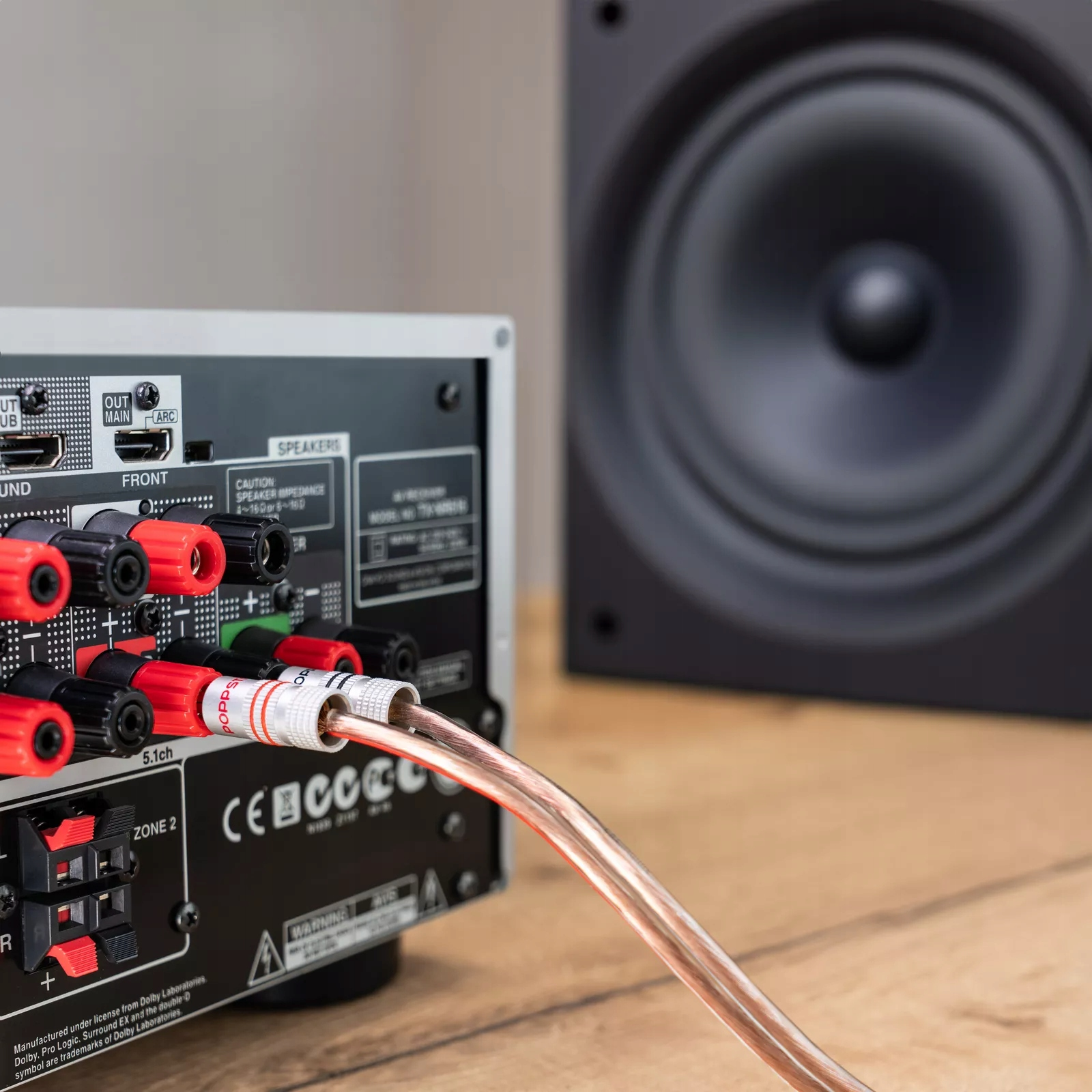 Połączenie amplitunera z kablami i subwooferem w tle.