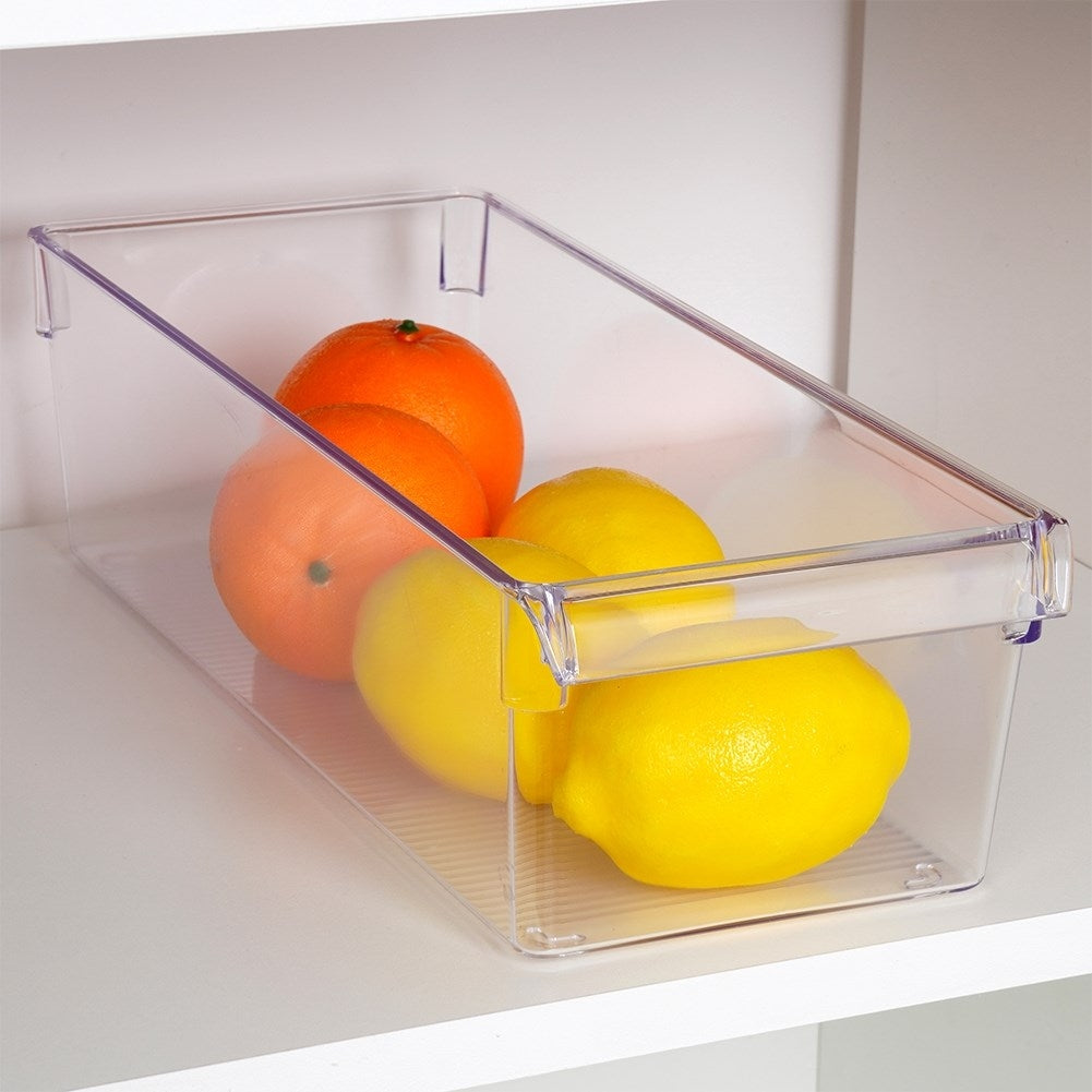 Naranjas y limones en un contenedor transparente en un estante blanco.