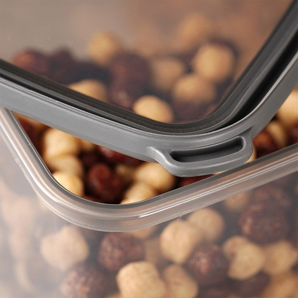 Primer plano de una tapa gris con asa, cubriendo un recipiente de cereales mixtos.